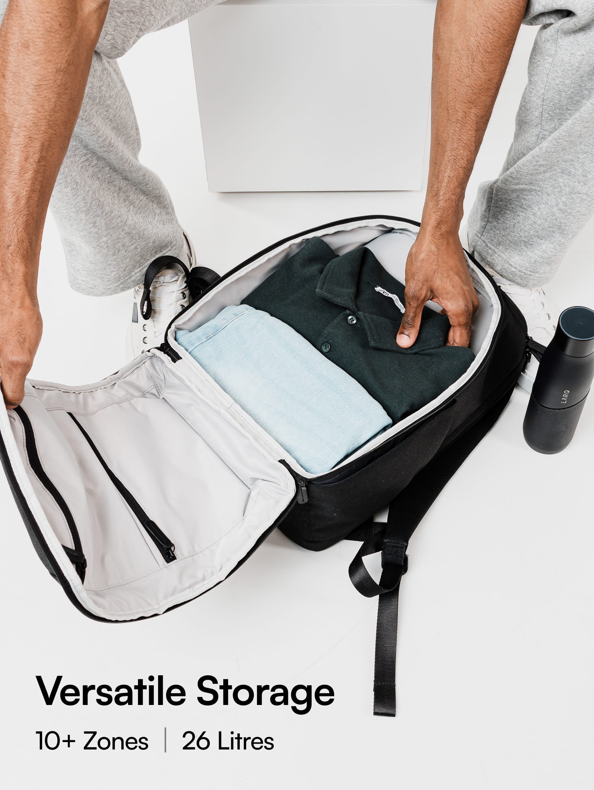 Person opening a black backpack with compartments on a white background, featuring text about storage capacity.